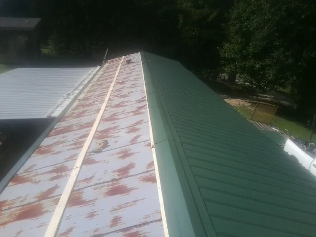 Old rusted panels beside newly installed green metal roofing — Wind Damage Roof Repair by Roofing Brothers in Vero Beach