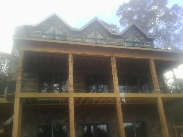Dormers and porch framing on a large log home under construction — Roof Coating work by our crew in Vero Beach