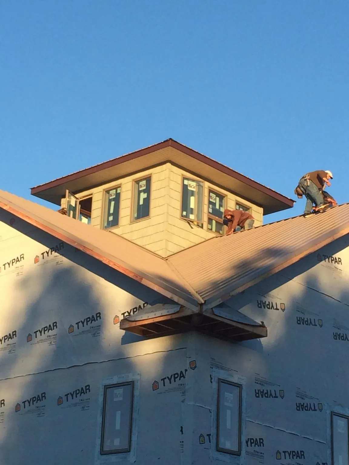 Roofers working around a rooftop cupola on a new metal roof at sunset — Roof Waterproofing in Vero Beach by Roofing Brothers